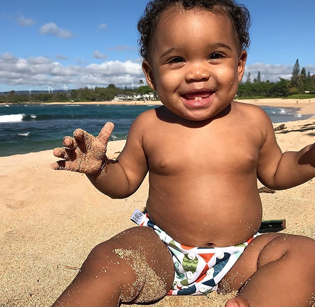 laughing baby on beach in swim diaper