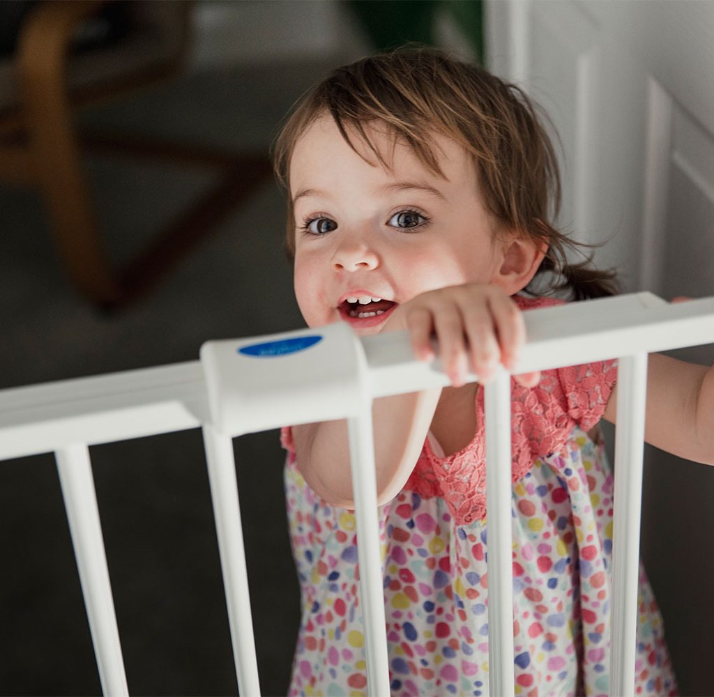 toddler at plastic baby gate