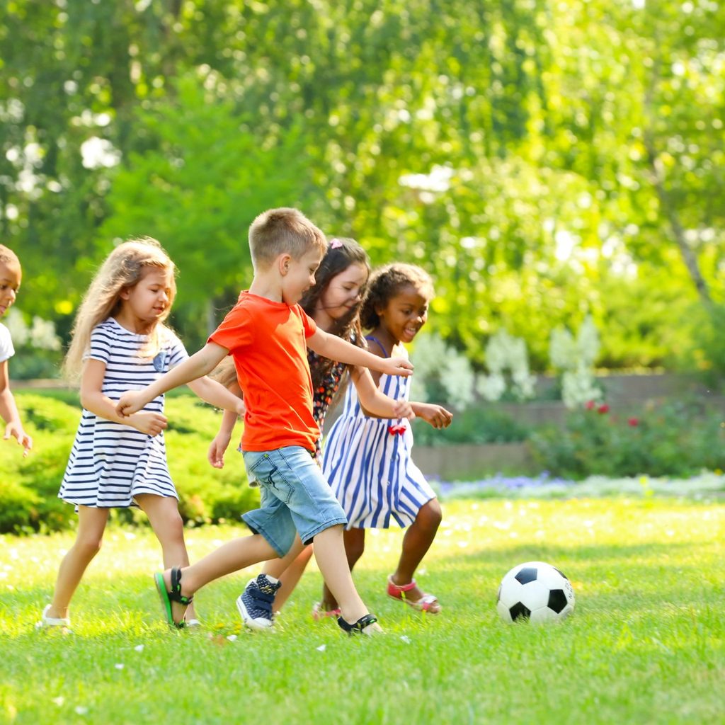 Group pf kids playing soccer in a park