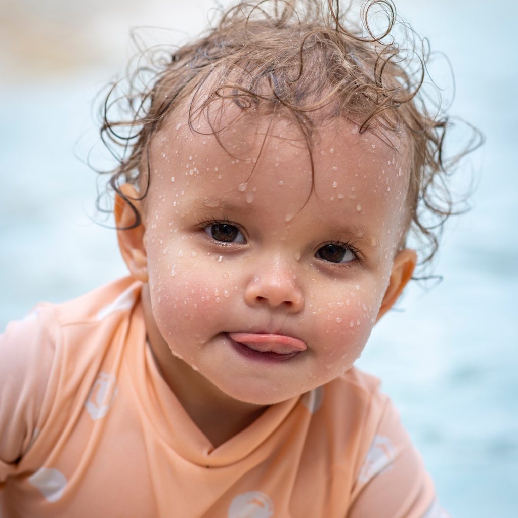 baby wet from swimming and wearing swim shirt