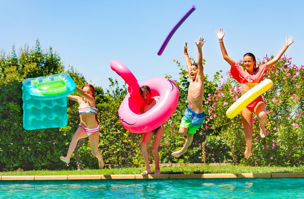 Kids jumping in pool using pool floats.
