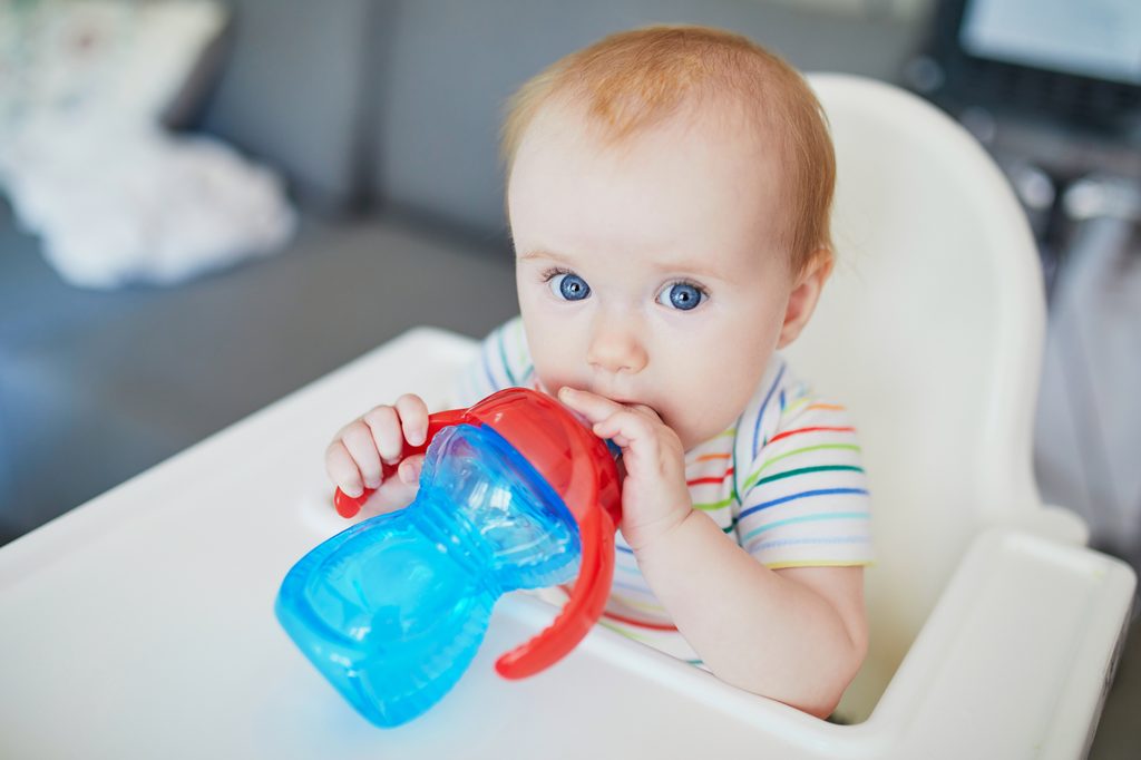 A baby drinking out of a sippy cup.