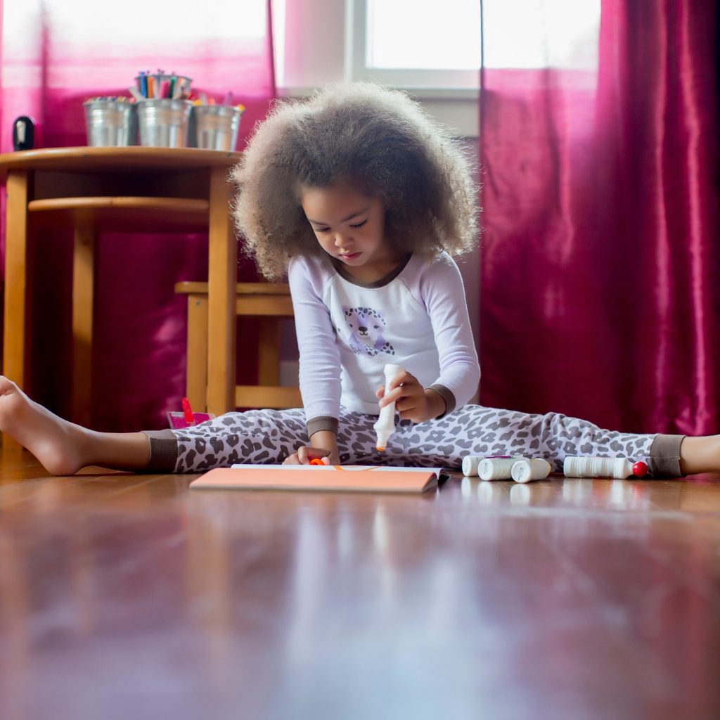 Young girl in pajamas om floor drawing