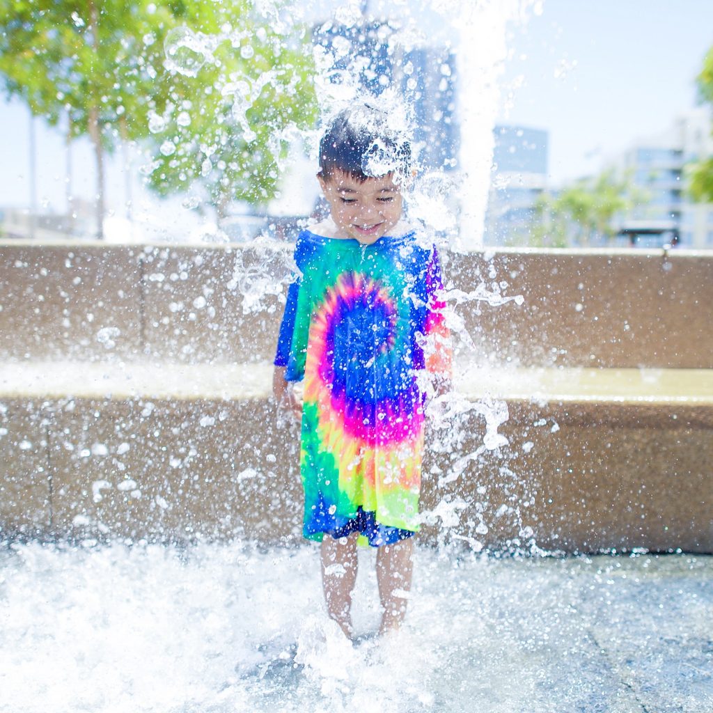 Boy wearing long shirt jumping in the water.
