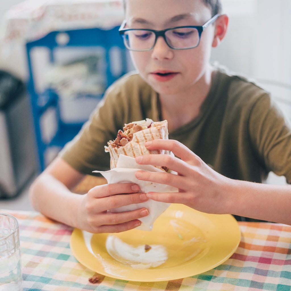 Young boy at table with chicken wrap