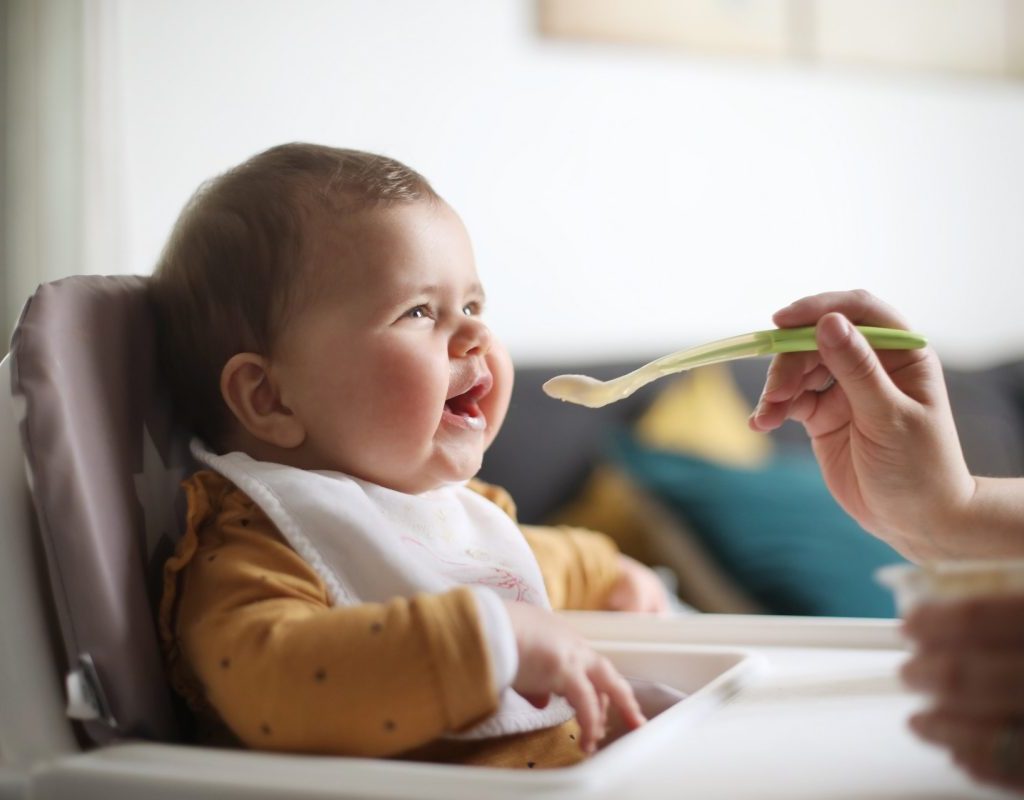 Baby in high chair at table eating