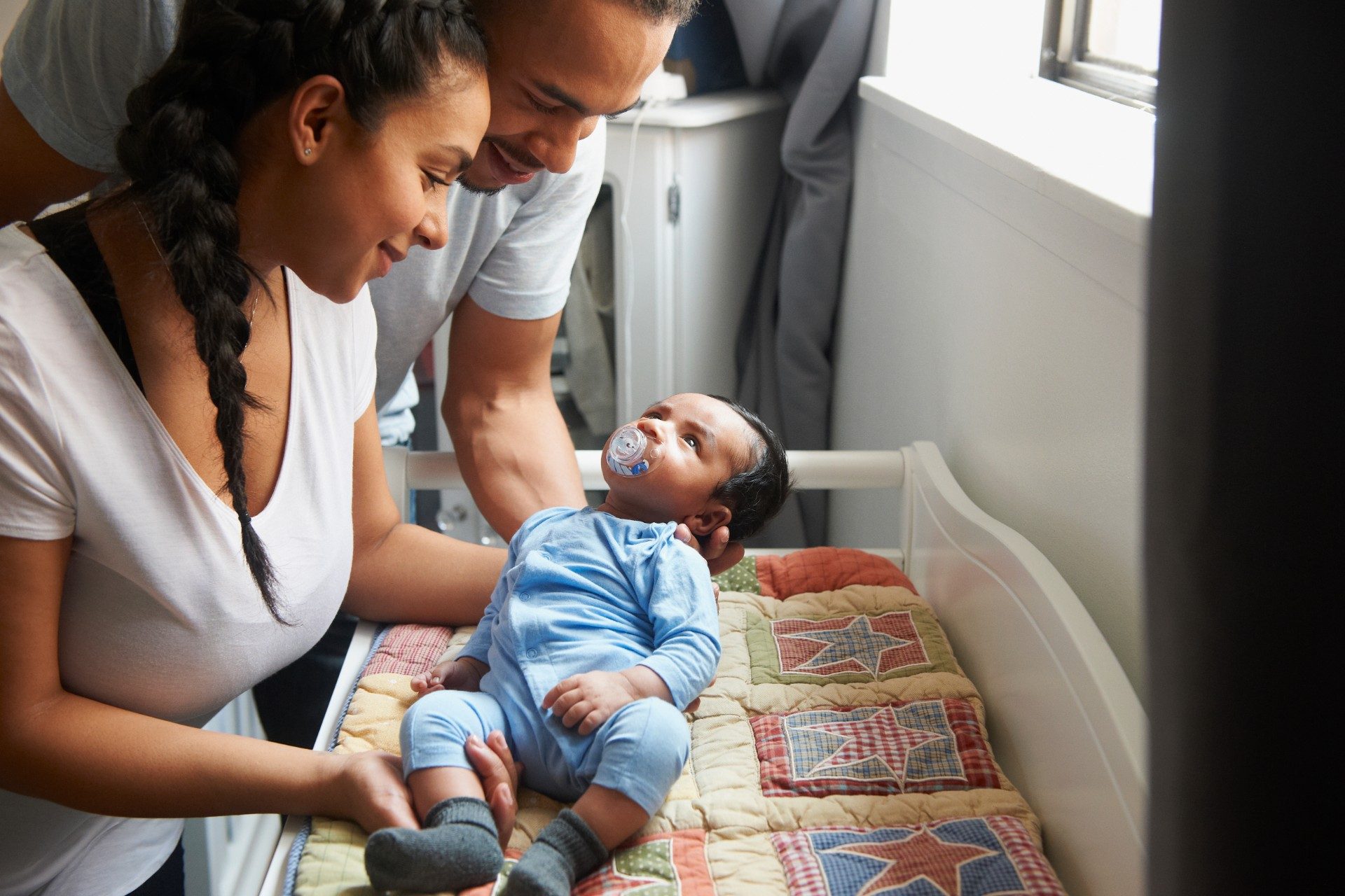 Woman and man holding child in crib