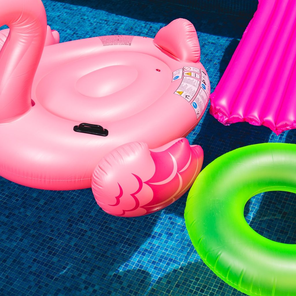 Four floating pool toys in a pool.