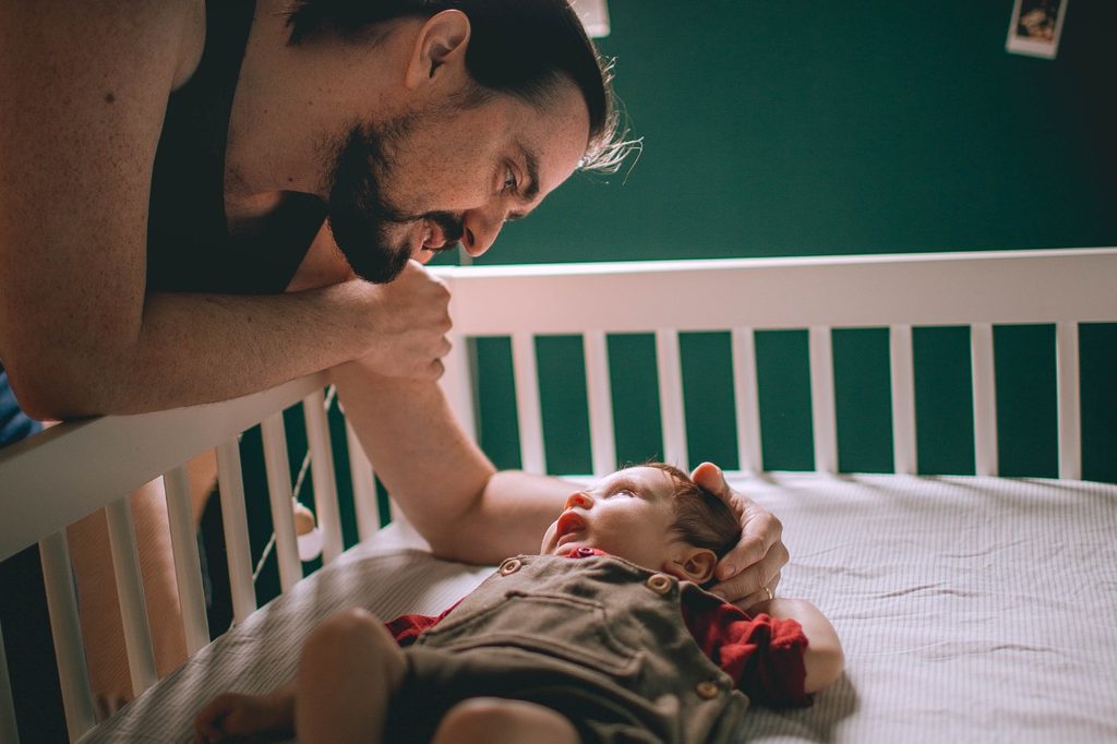Man comforting child in crib.