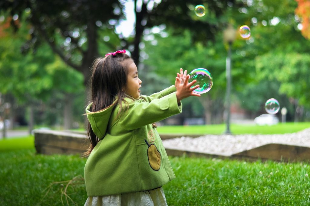 Toddler outside playing with bubbles