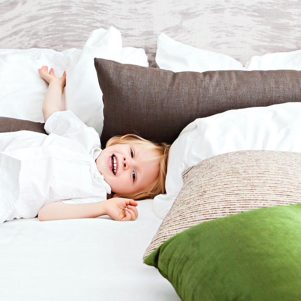 little boy laying in bed with a bunch of pillows