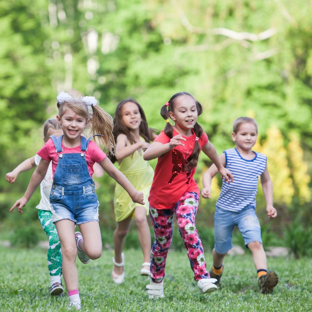 Group of children running in capture the flagg in a park