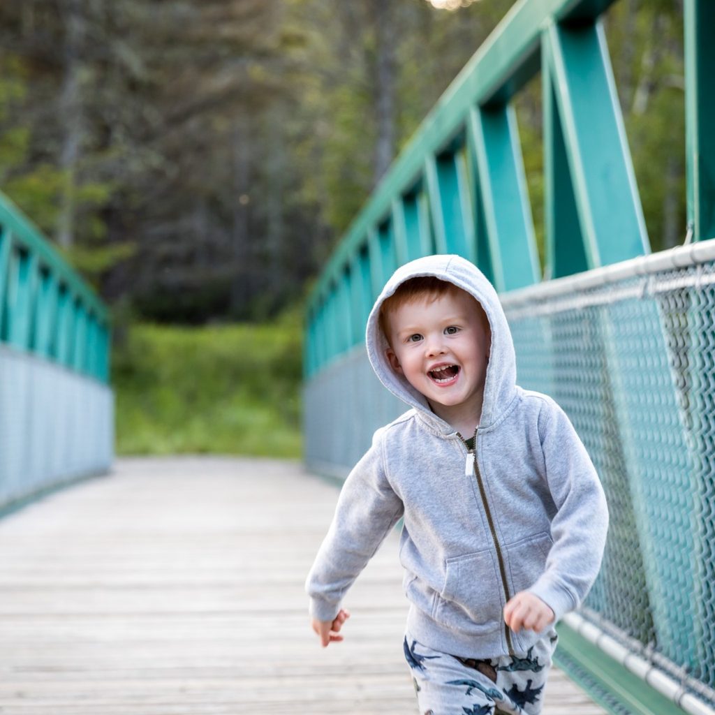 Boy in hoodie crossing small bridge