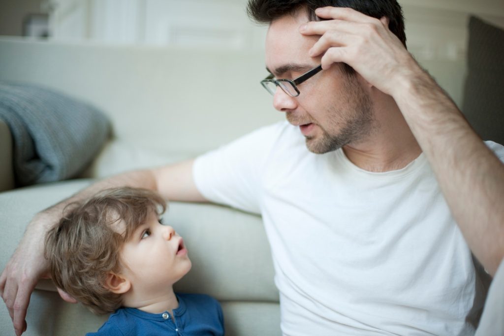 Father talking with son on couch.