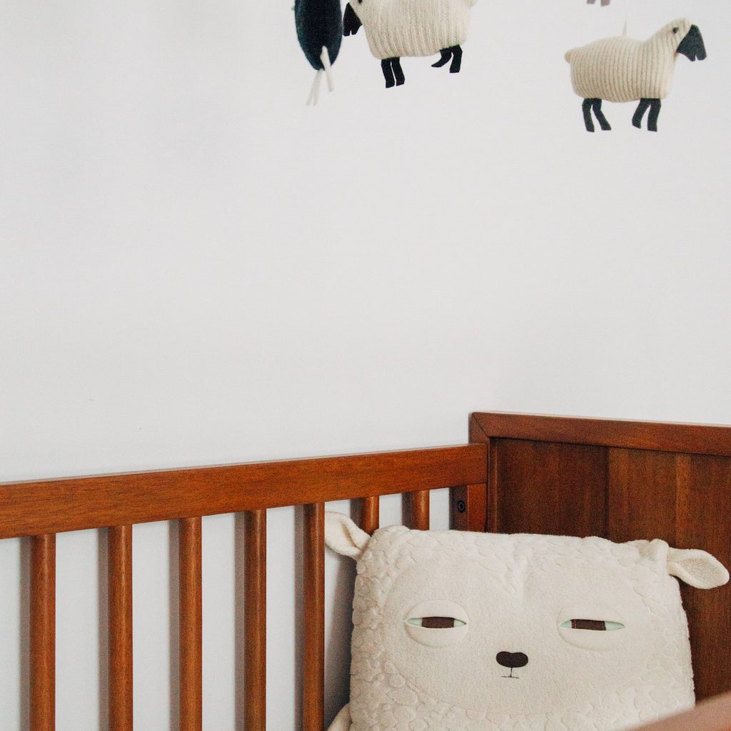 crib with sheep pillow and sheep mobile overhead