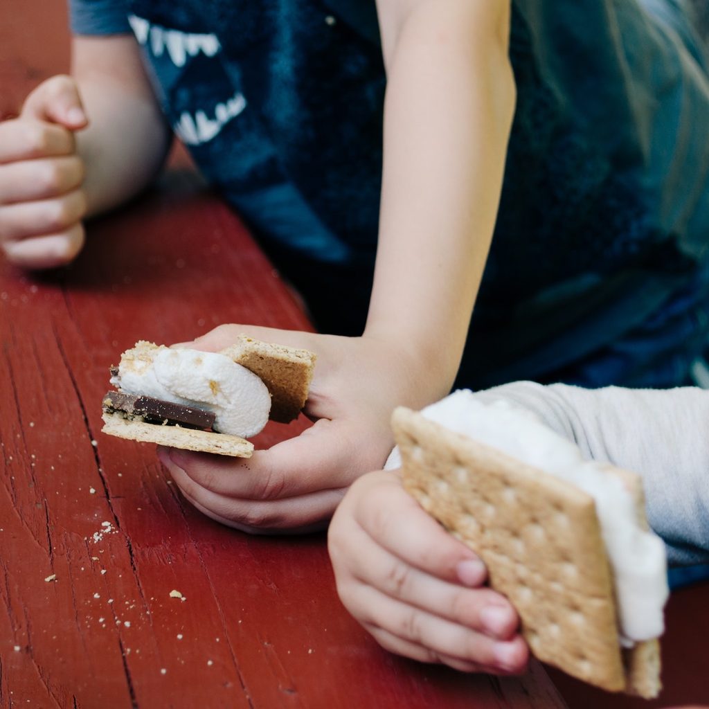 two kids eating s'mores at picnic table