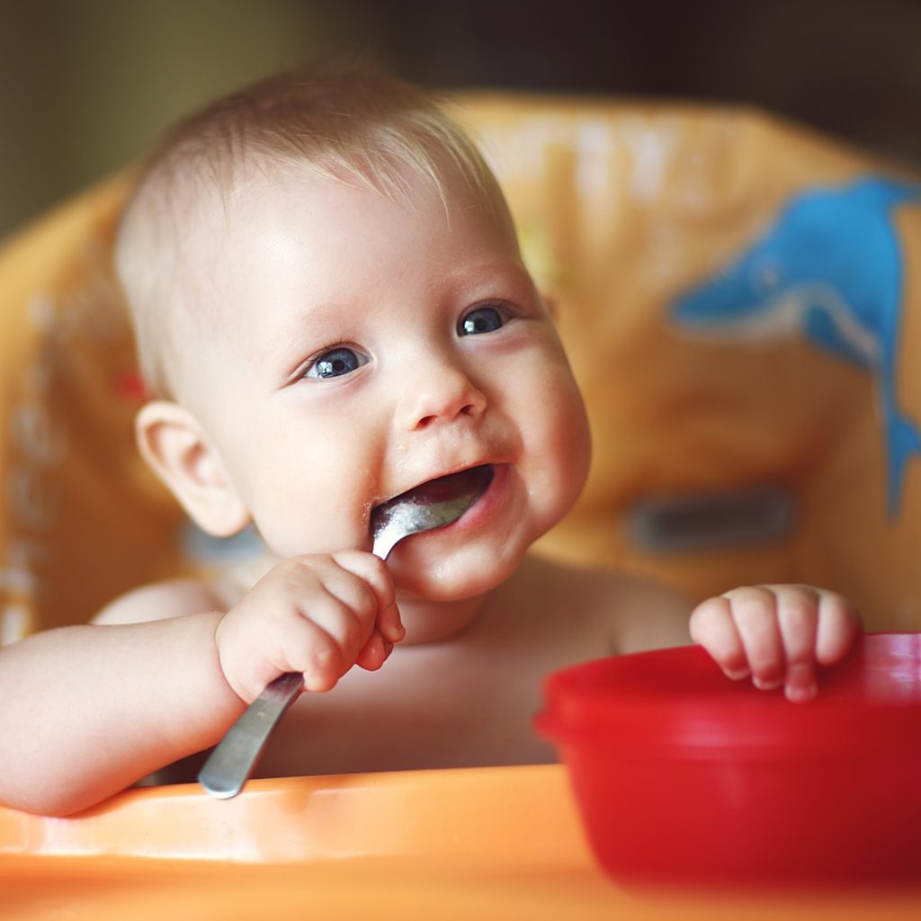 Happy toddler eating from red bowl