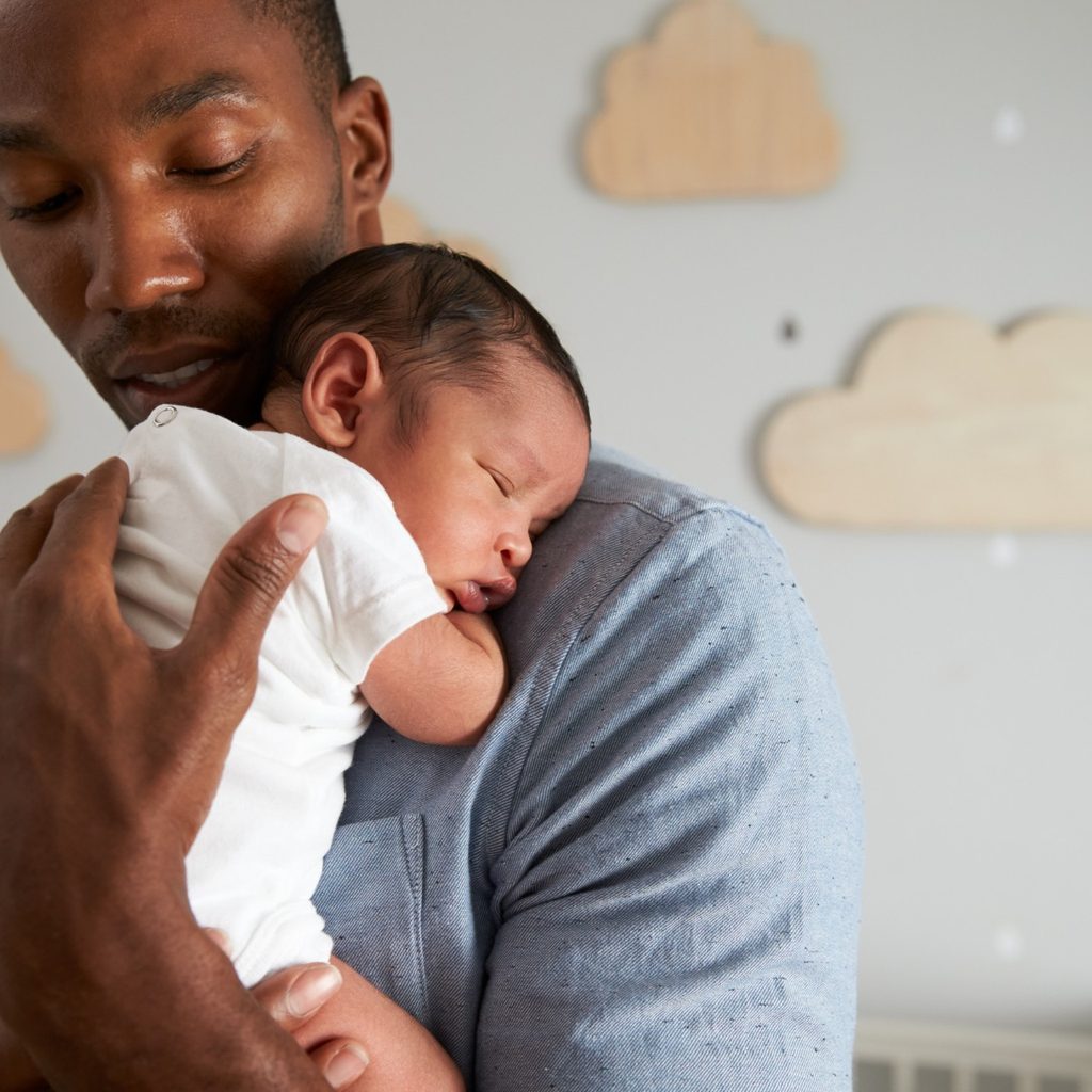 Father holding baby in nursery.