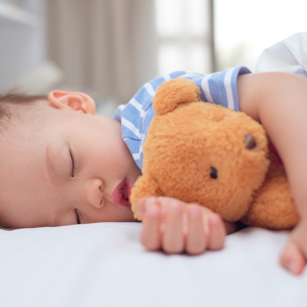 Toddler boy sleeping with Teddy bear
