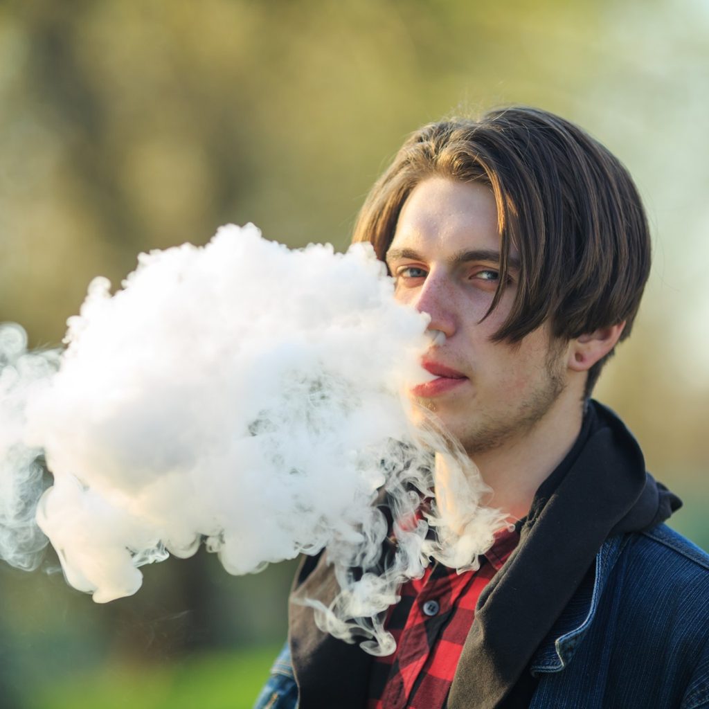 Teen boy vaping outside