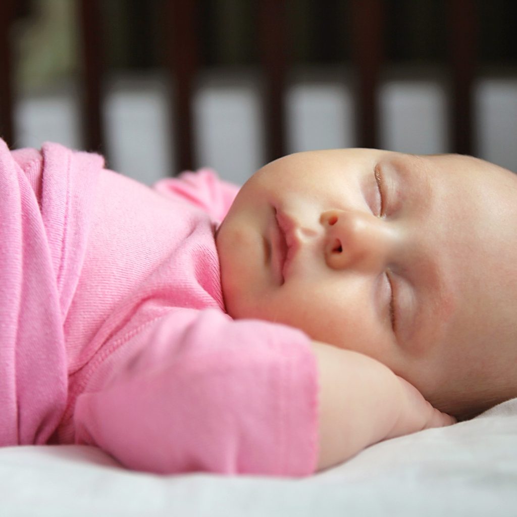 Infant girl sleeping in crib