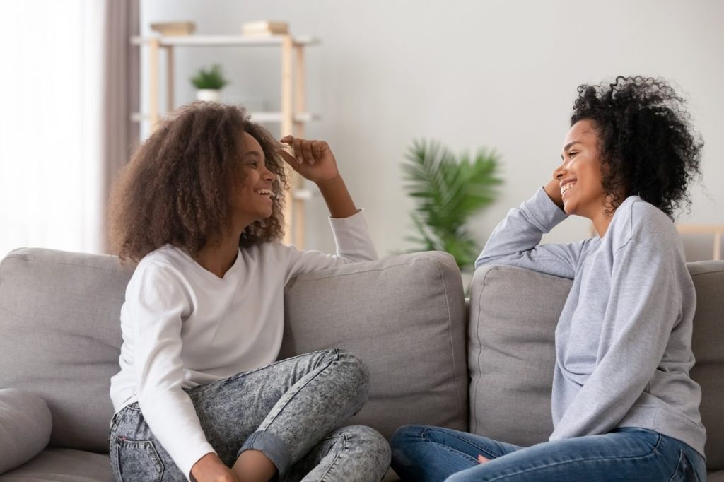 Mother and teenage daughter on couch talking.