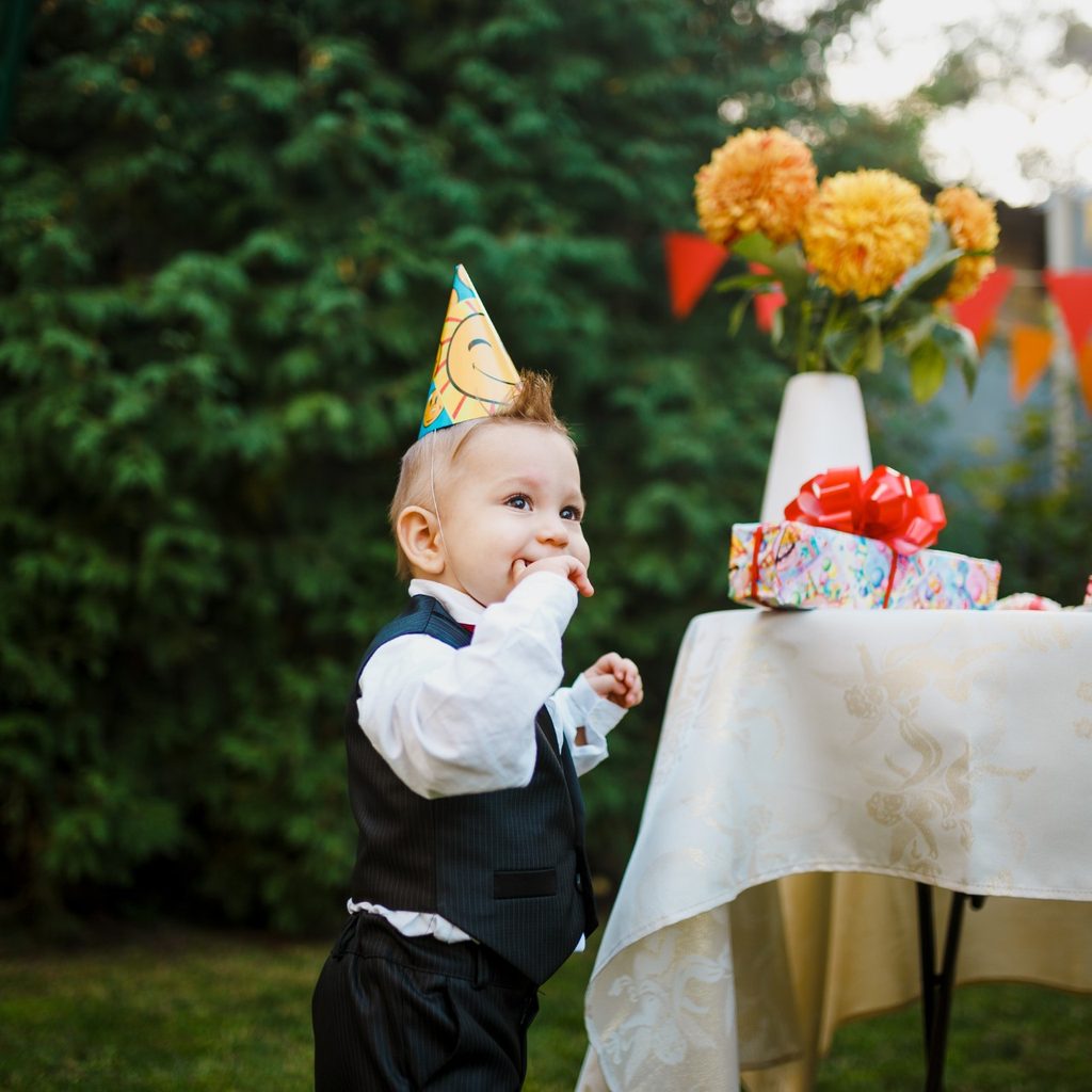 Toddler near table at a backyard birthday party