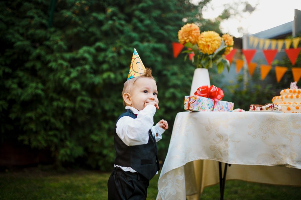 Toddler near table at a backyard birthday party