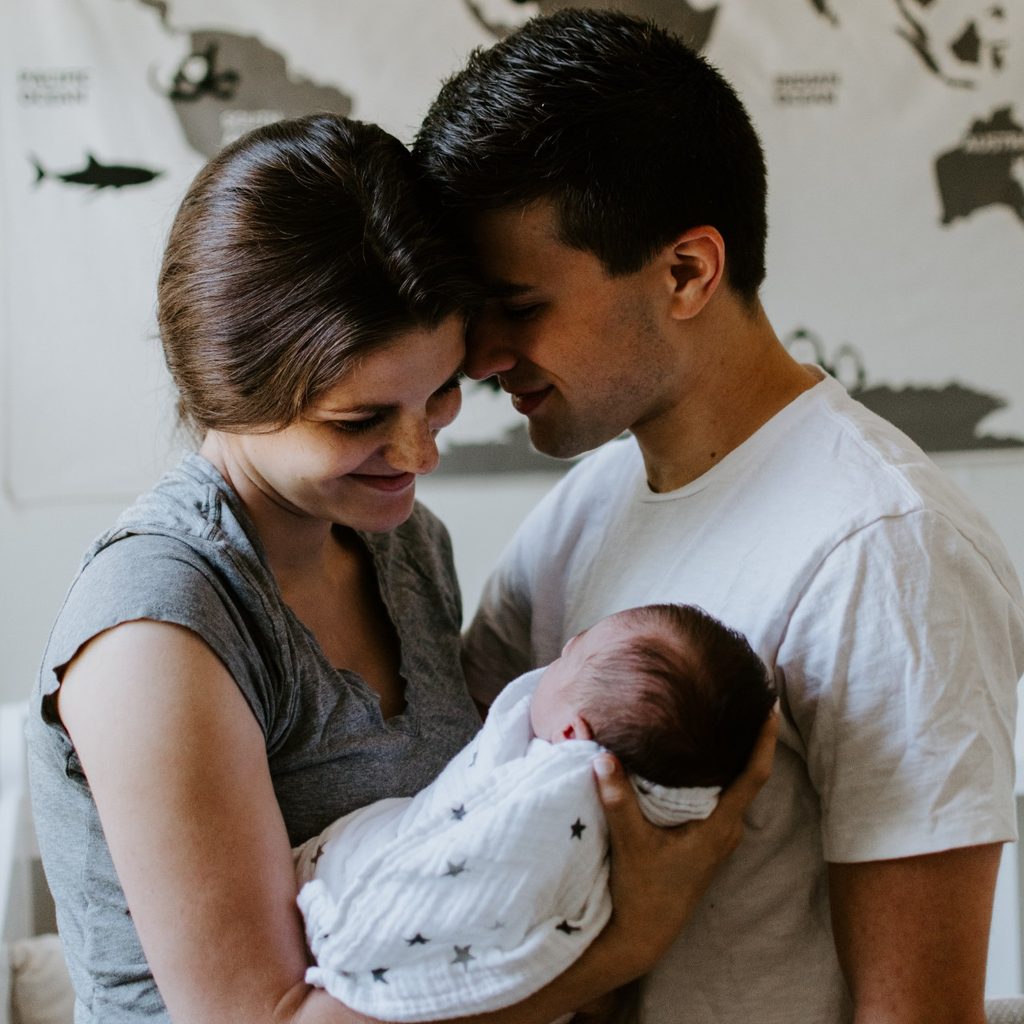 Mother and father holding child near map