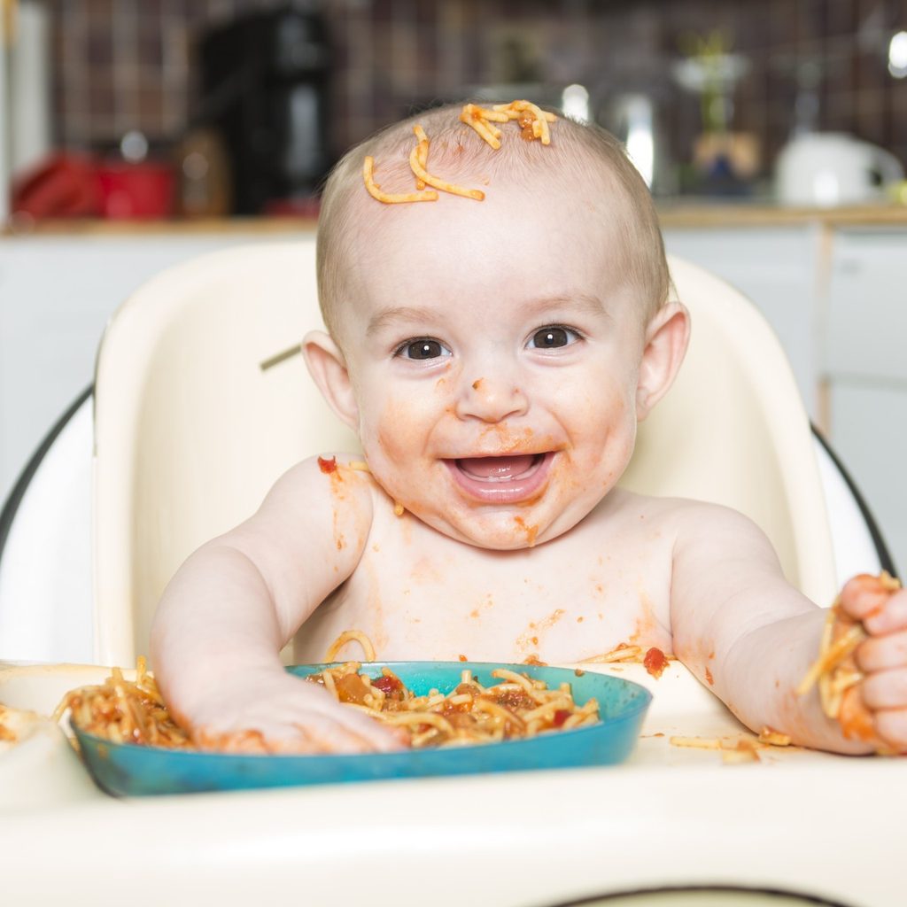 Smiling baby eating and making a mess