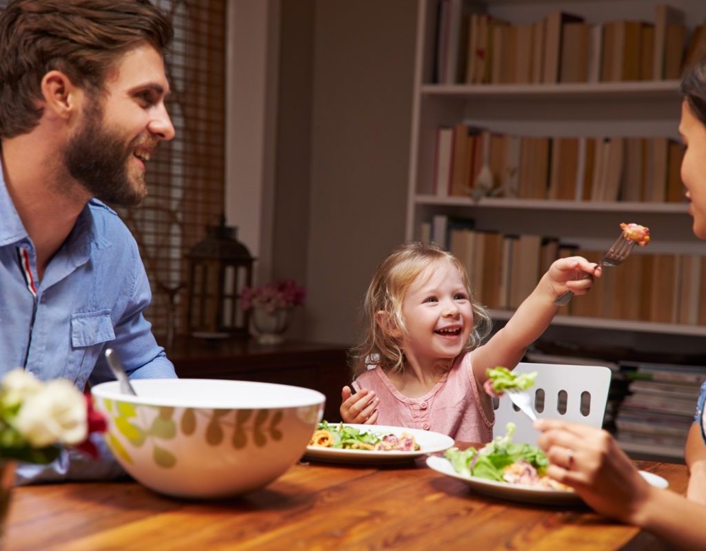 Family of three eating dinner at table at home