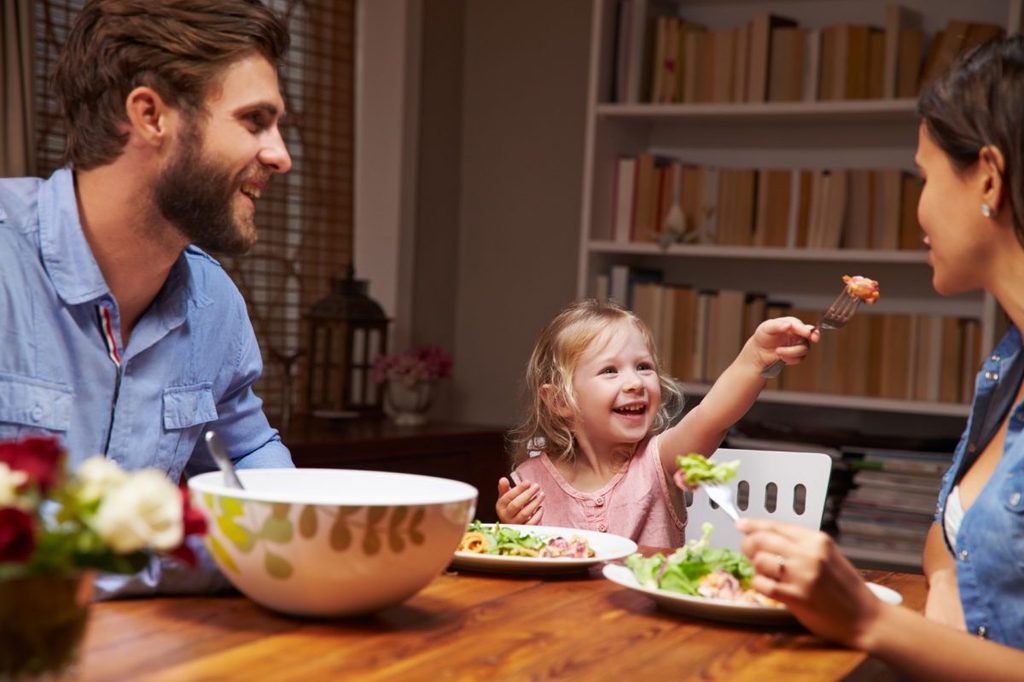 Family of three eating dinner at table at home