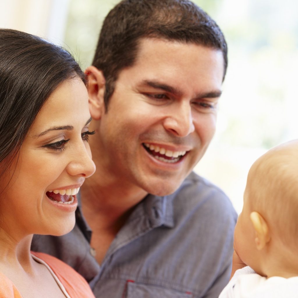 Smiling parents talking to their baby