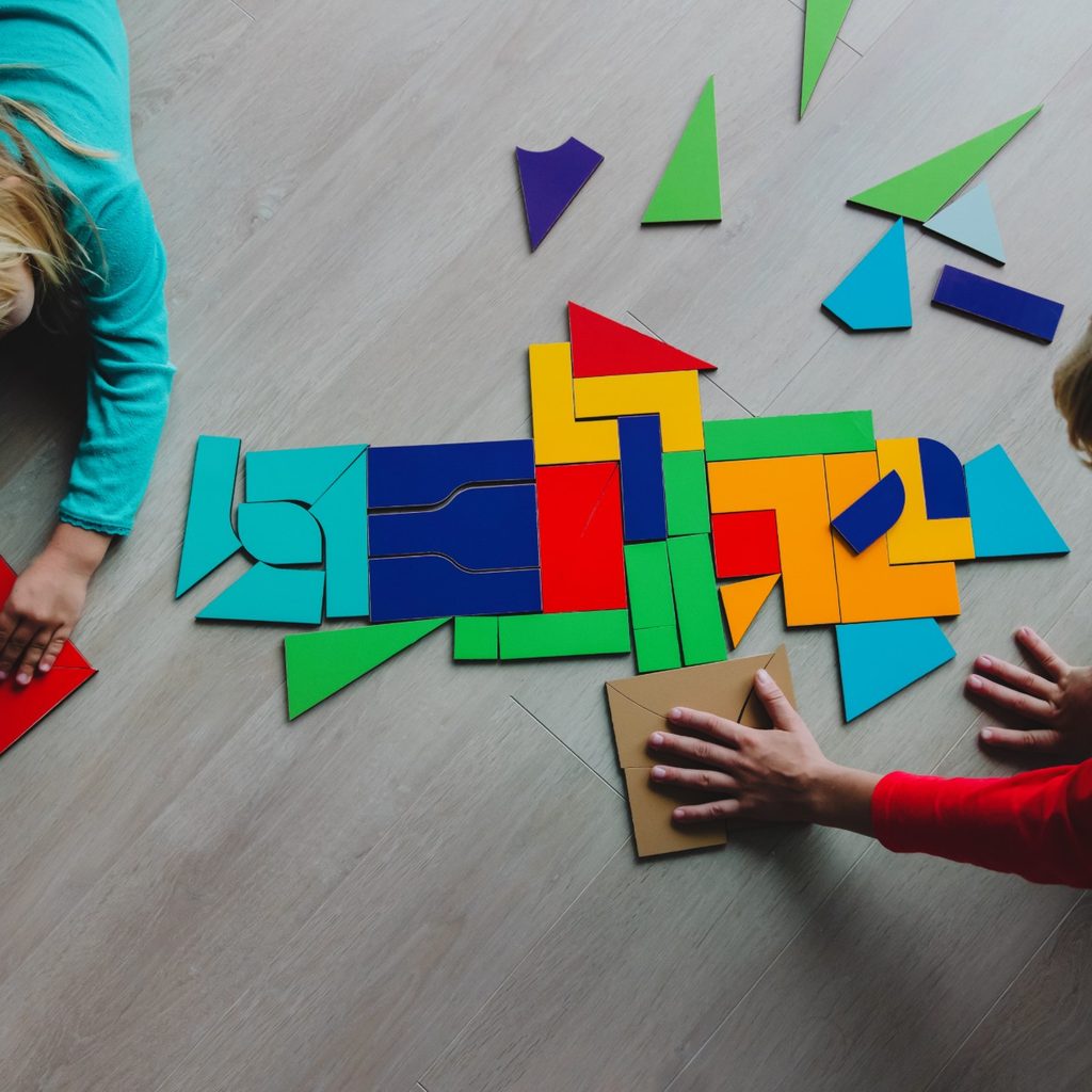 Two young kids playing with tangram puzzle