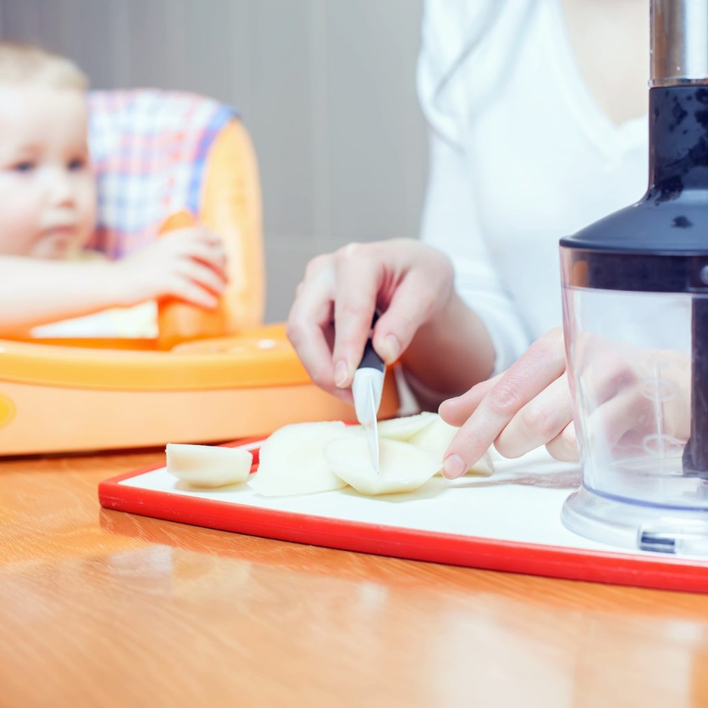 Mother preparing baby food for a blender