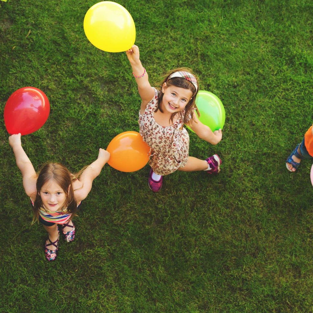 Three children playing with balloons outside