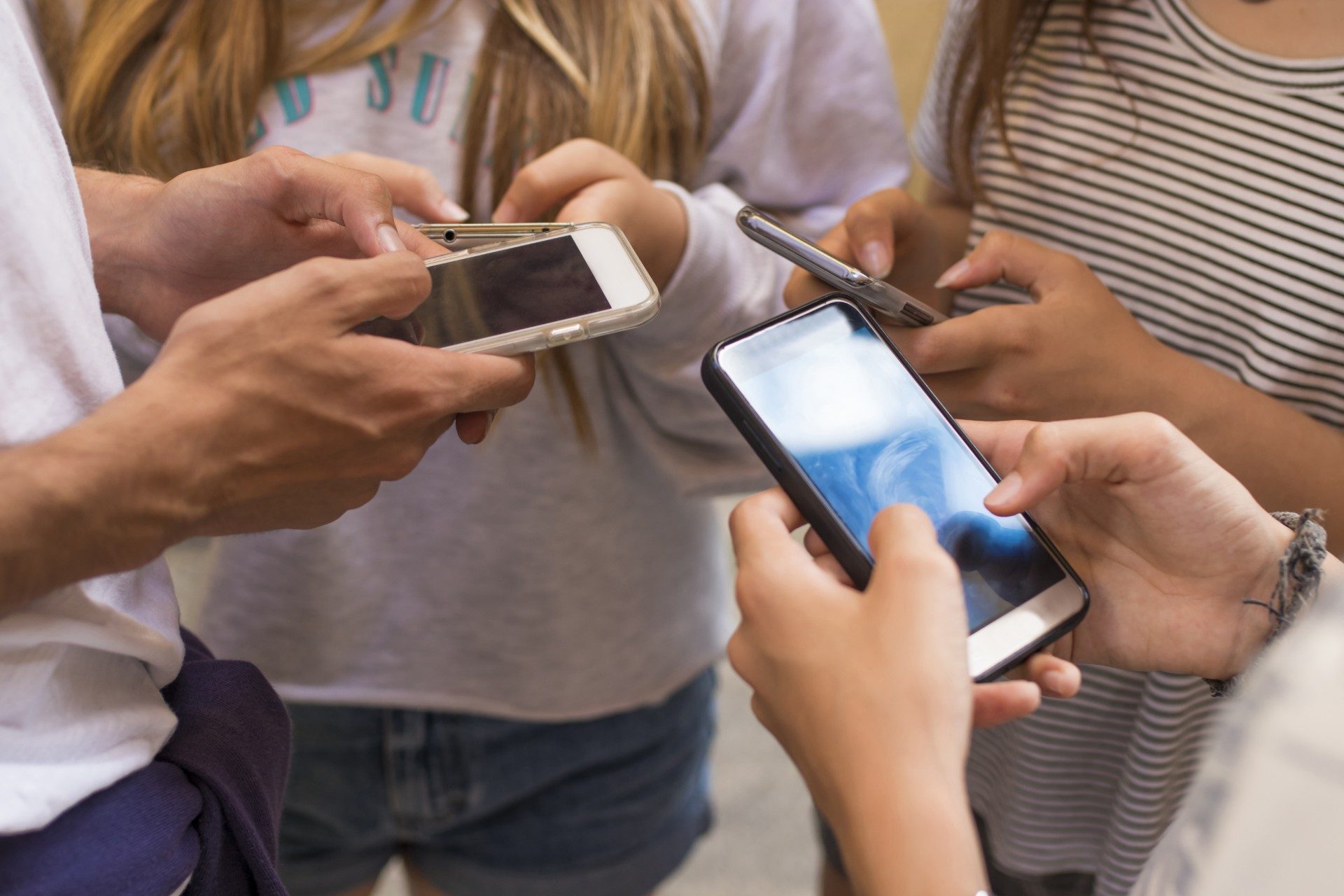 Group of teens using smartphones.