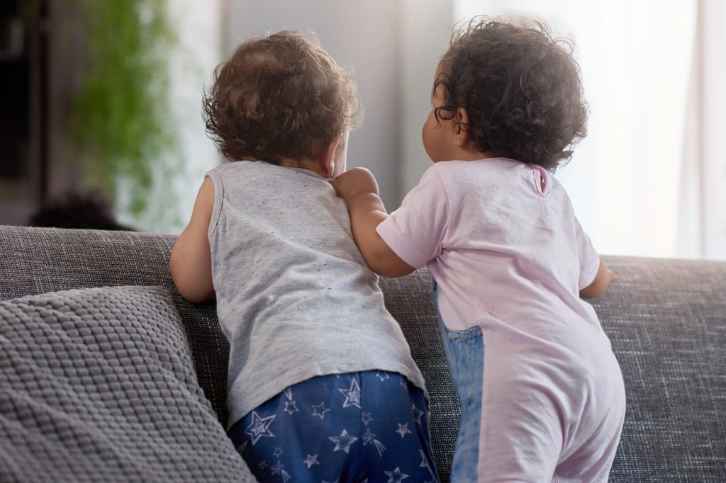 Boy and girl toddlers sitting on a couch.