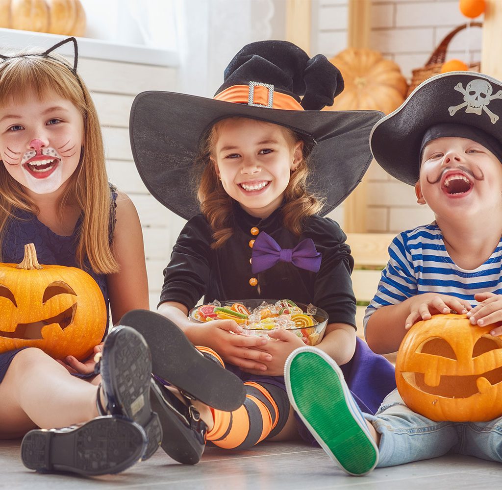 three kids laughing and wearing costumes