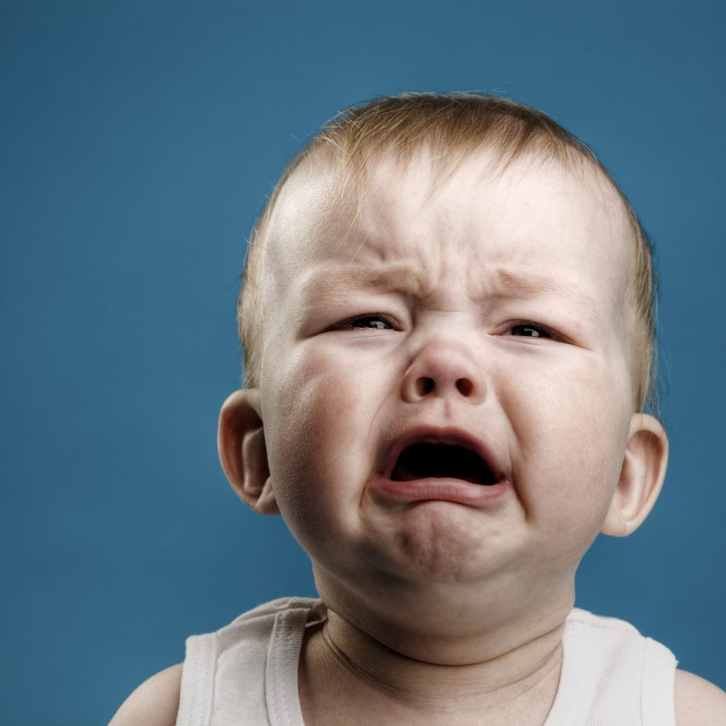 Young boy crying against blue wall