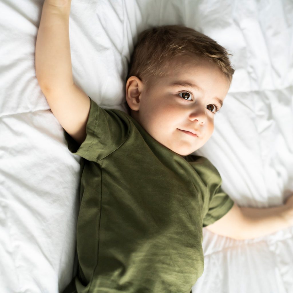 Toddler boy lies awake in bed