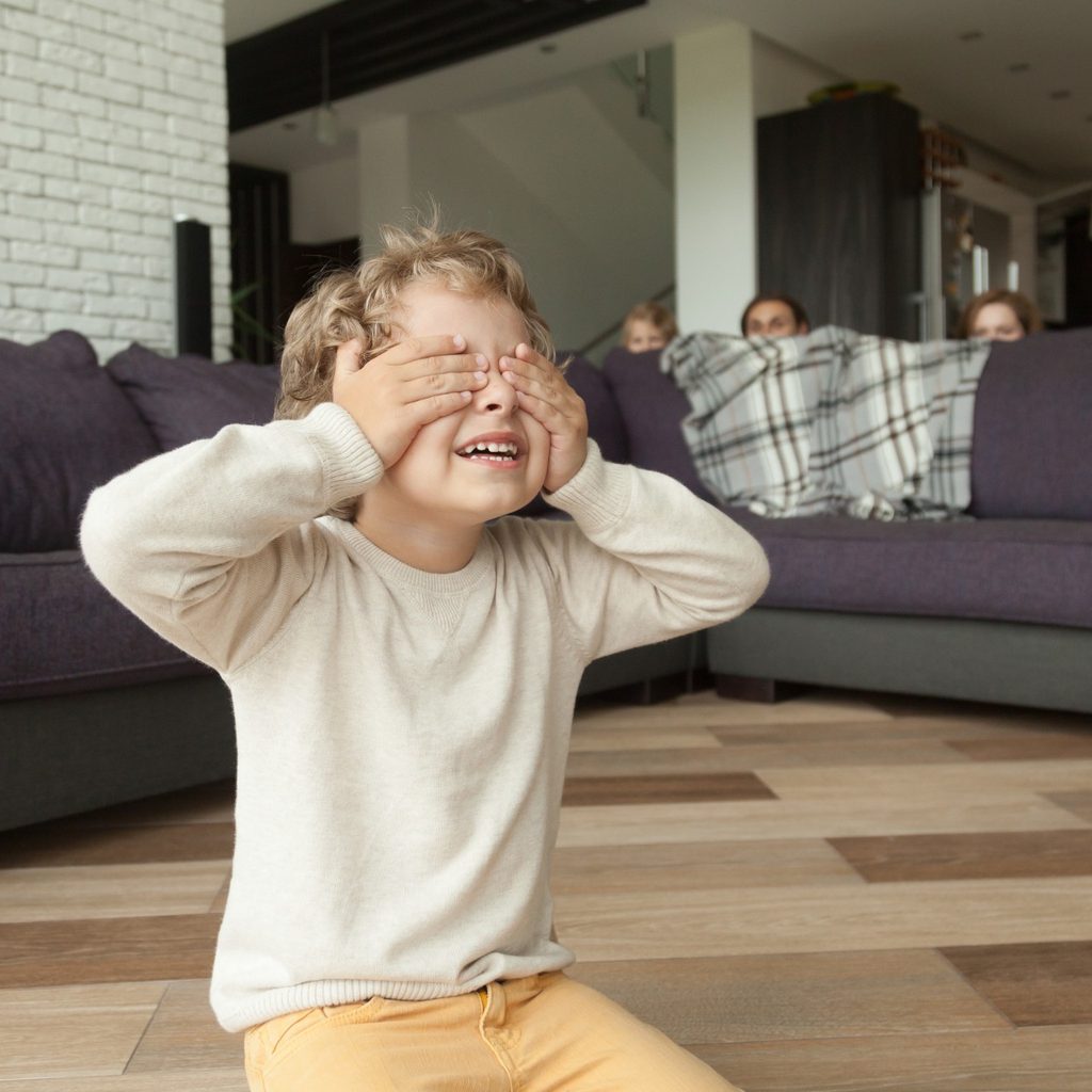 Child and parents playing hide-and-seek in their living room