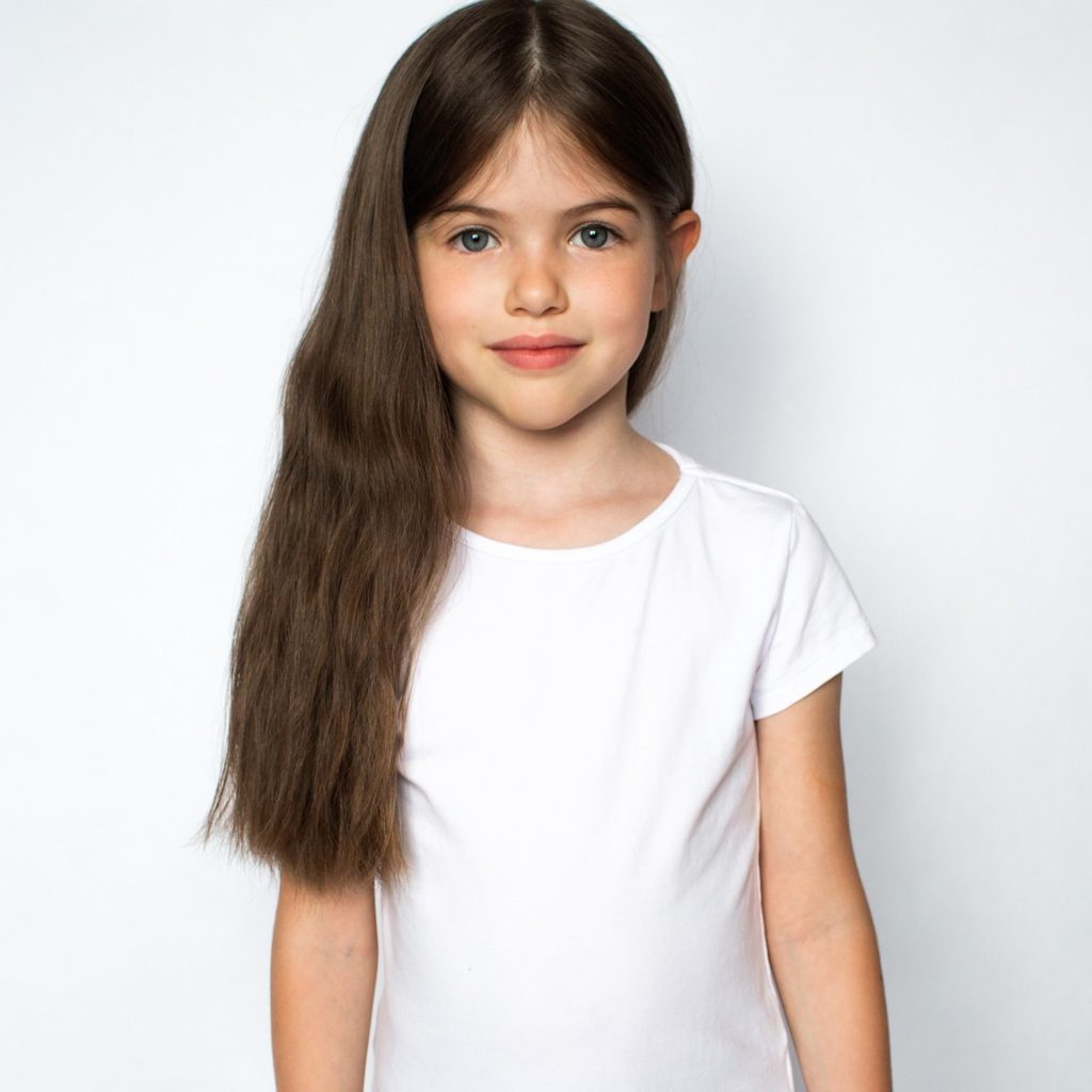 Young girl posing against a white wall
