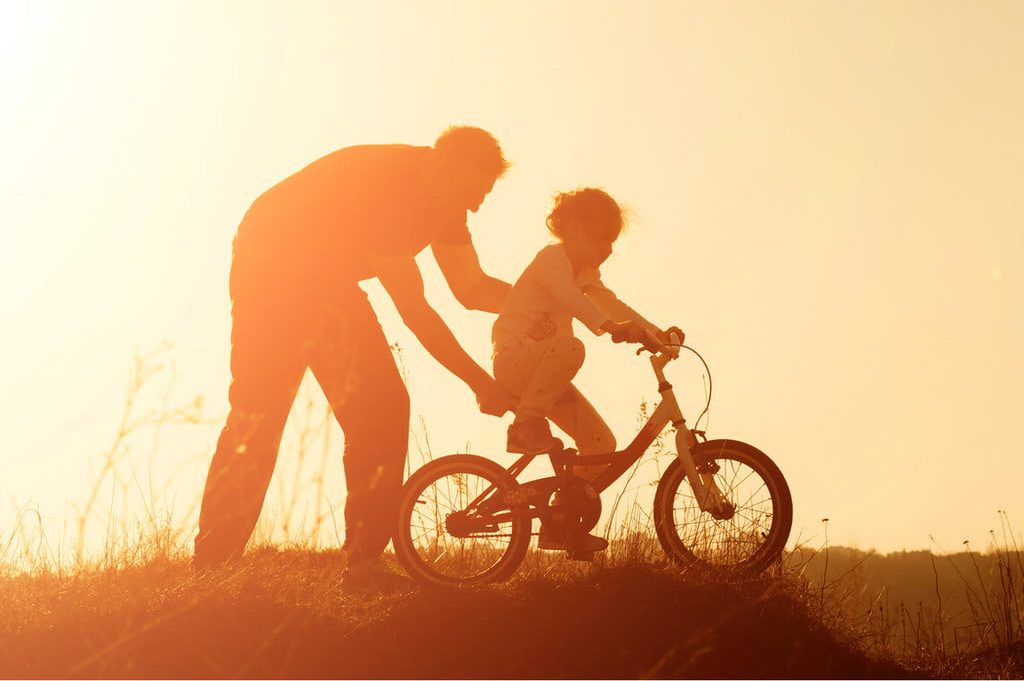 Adult teaching a child to ride a bicycle