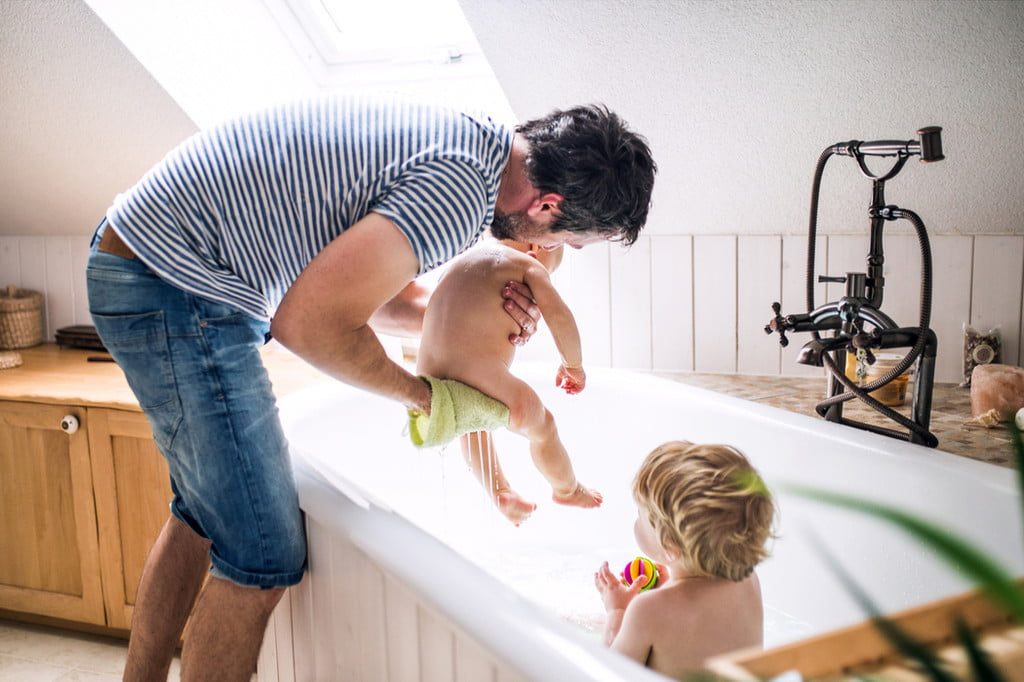 A parent putting kids in the bath