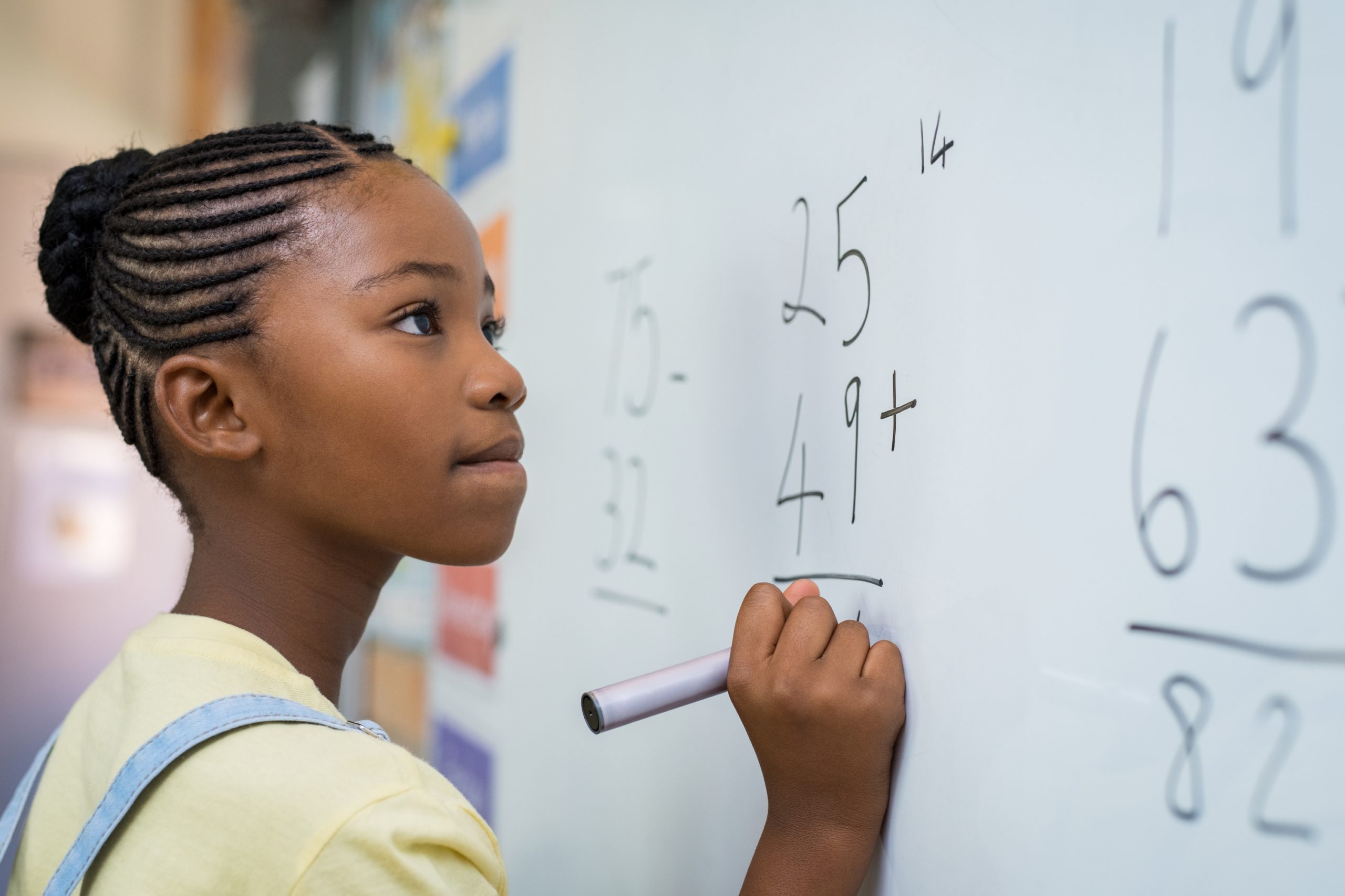 Student solving math problem on a white board