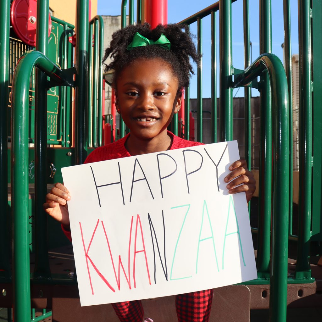 Young girl with Kwanzaa sign on a playground
