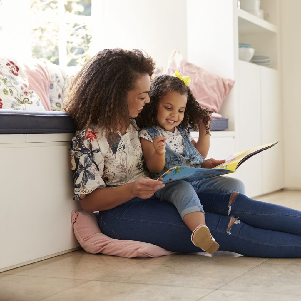 Mother reading a book to her daughter.
