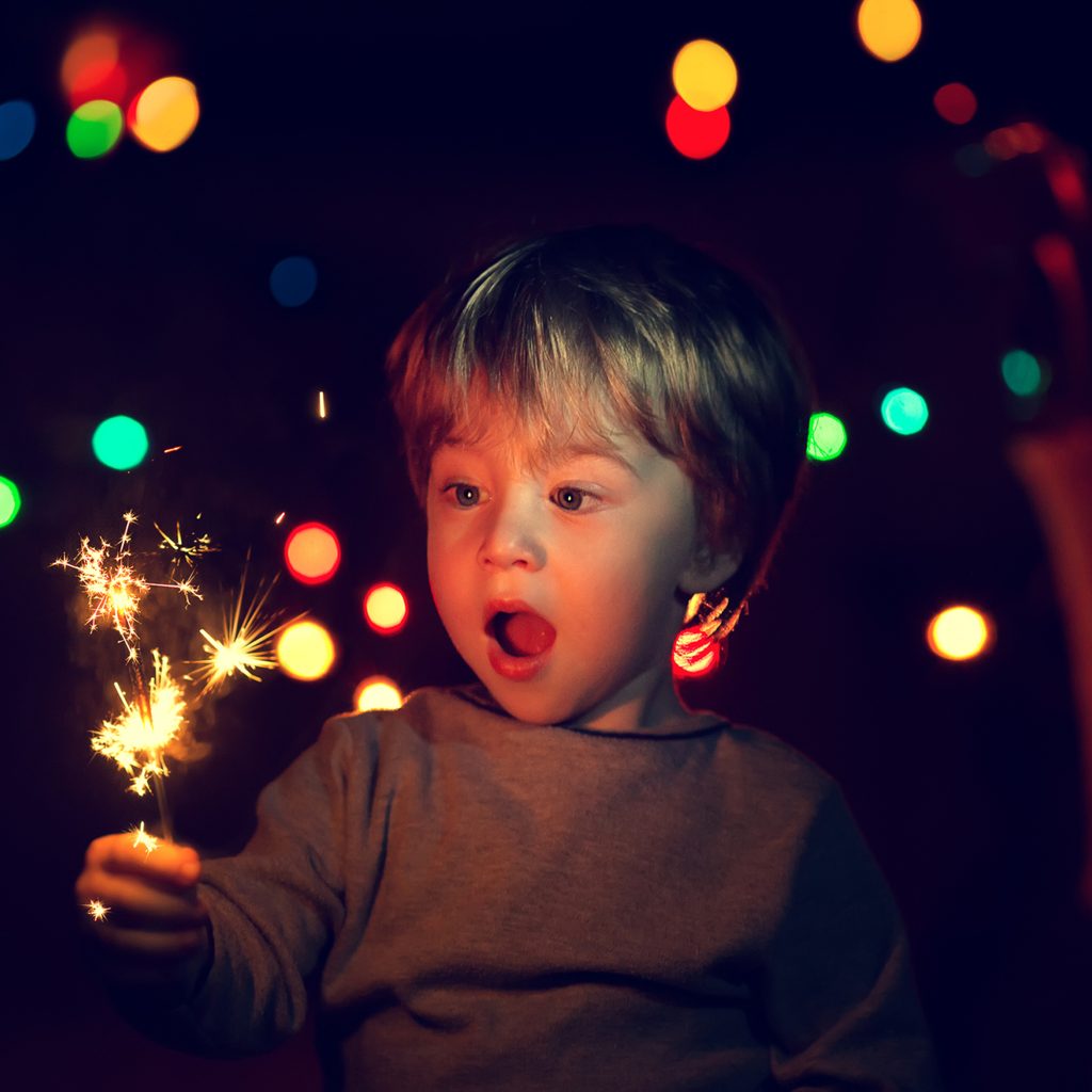 Toddler boy holding a sparkler at a party