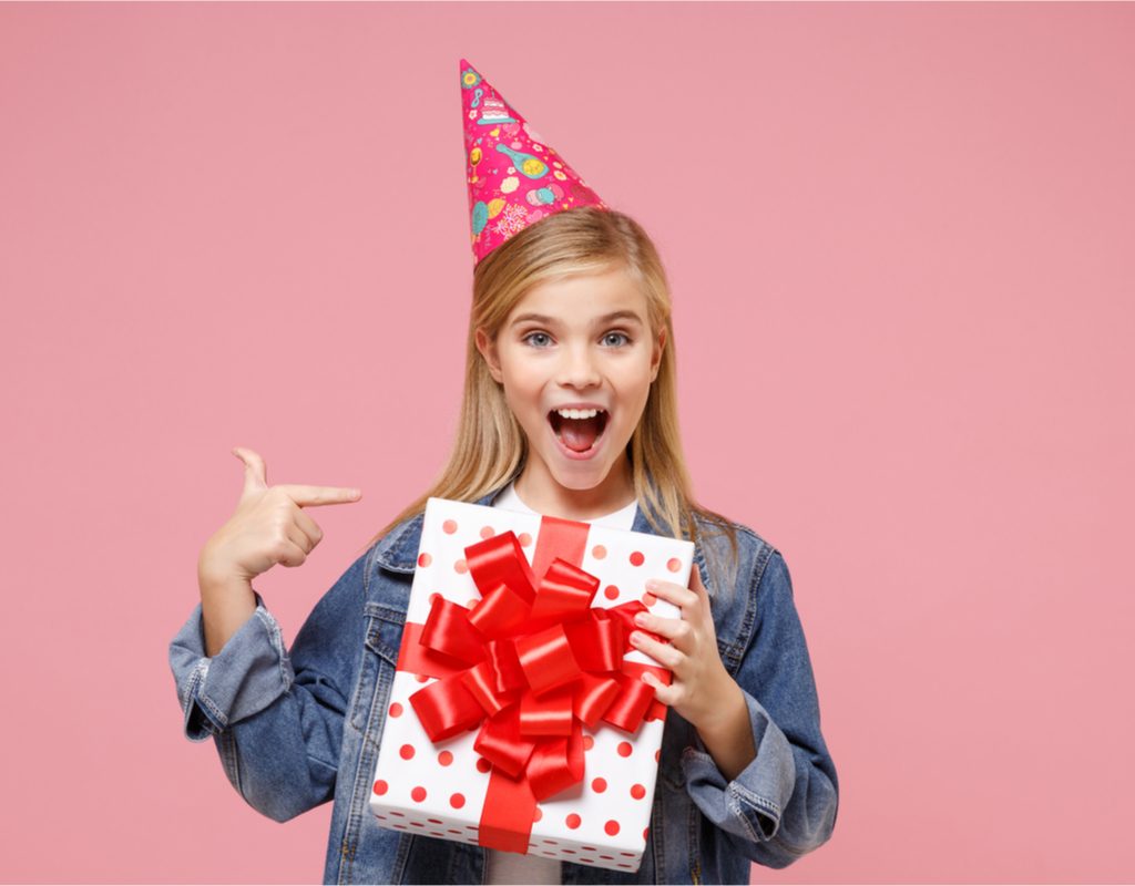 Pre-teen girl smiling, holding birthday present